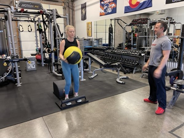 Trainer Joe coaching a client through a medicine-ball balance exercise.