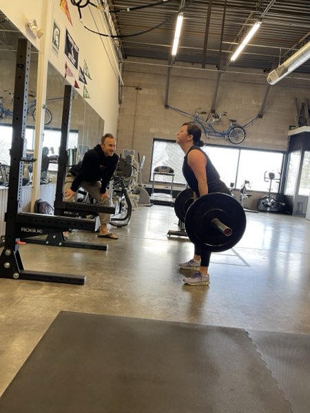 Trainer Joe coaching a client through a barbell deadlift.