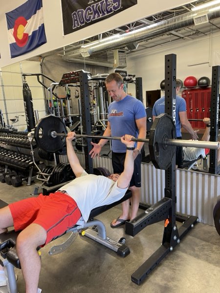 Trainer Joe spotting a client on a barbell bench press.