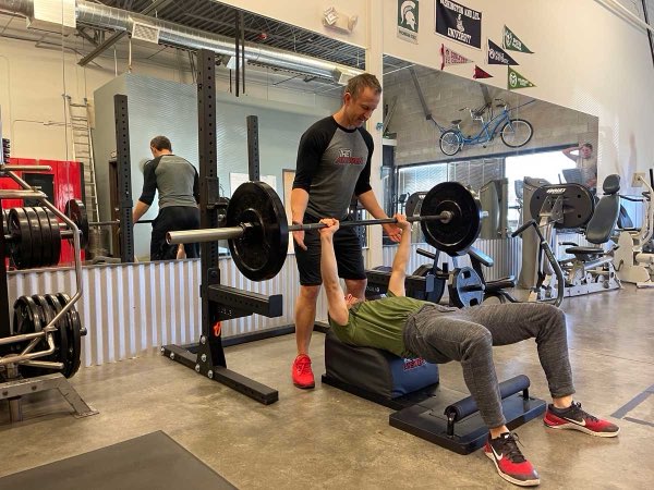 Trainer Joe spotting a client during a strength session at the studio.